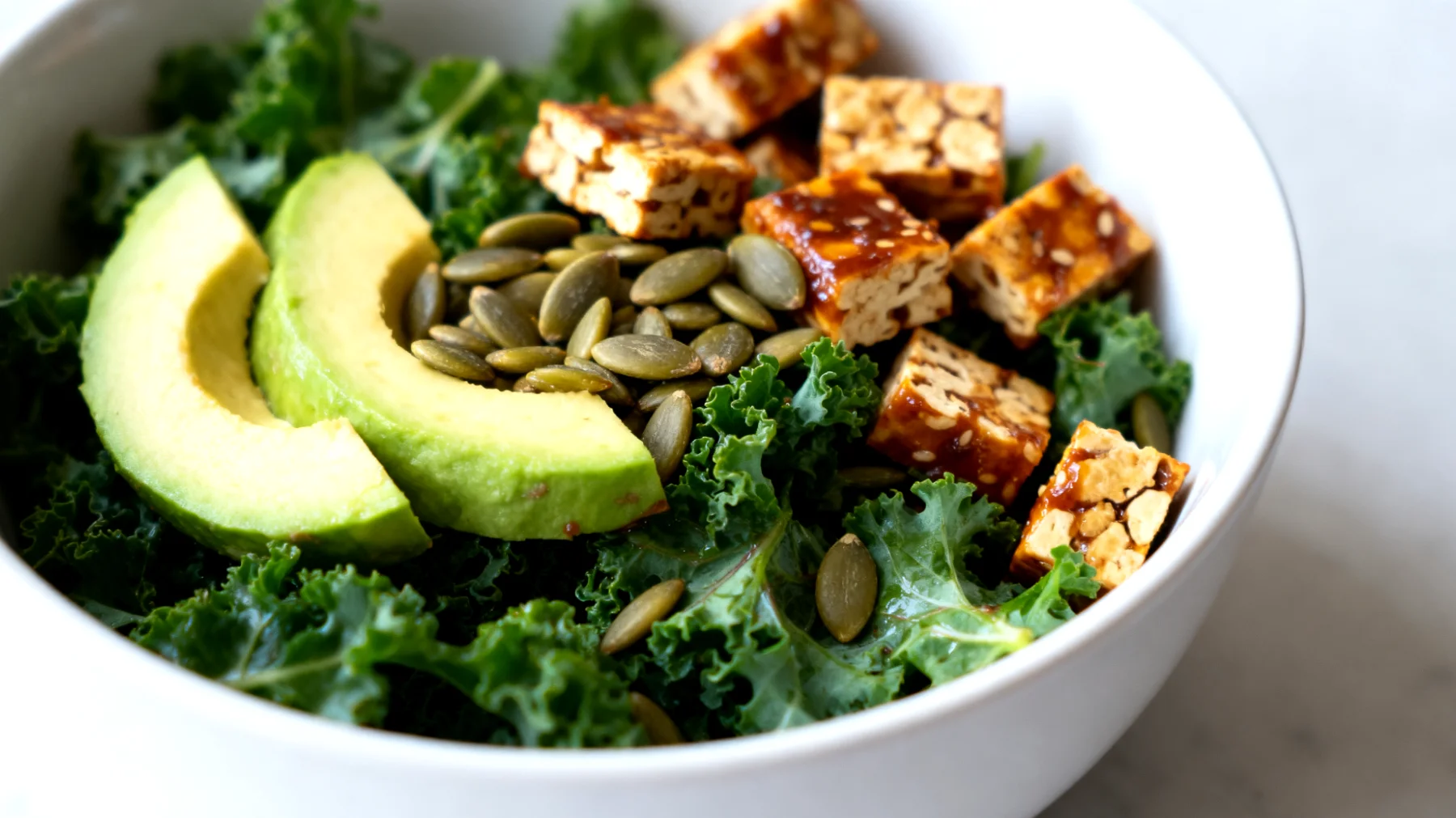 Insalata di cavolo nero (kale) con avocado, semi di zucca e tempeh marinato"